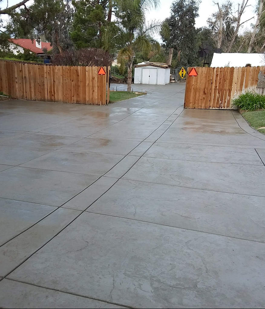 A concrete driveway with a backdrop of palm trees and a sunny sky.