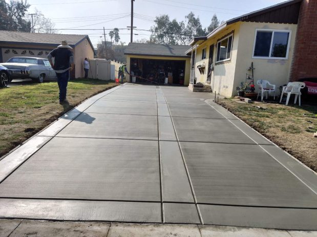 Concrete driveway featuring a smooth surface with a light grey color, leading up to a modern home.
