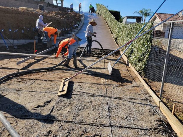 Concrete being installed on a driveway by construction workers.