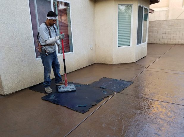 A person mopping a concrete patio.