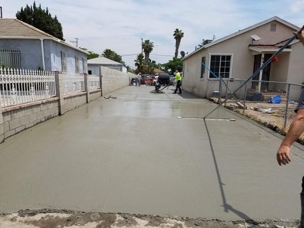 A man pouring concrete on a street during construction work.