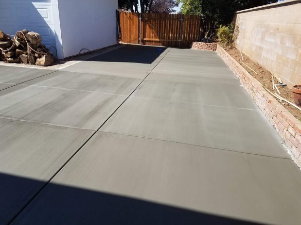 A concrete driveway with a backdrop of palm trees and a sunny sky.