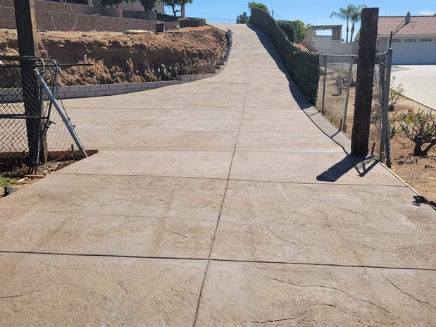 A concrete driveway with a fence and a gate.
