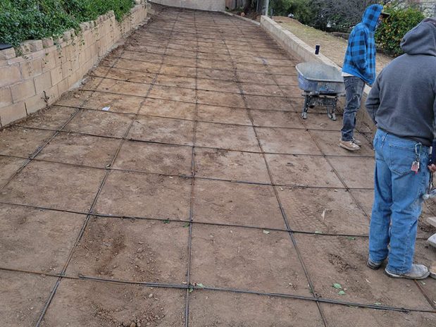Men laboring on a concrete driveway.