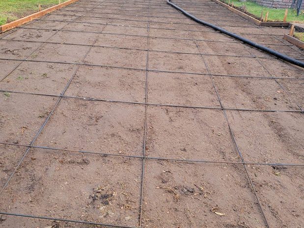 A dirt road enclosed by a fence, leading through a rural landscape.
