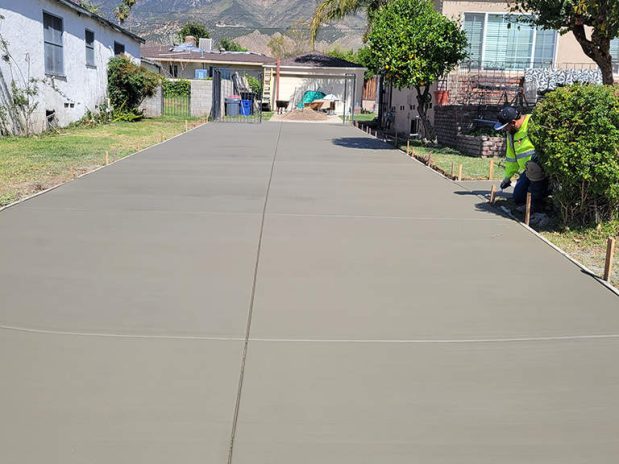 Concrete driveway with palm trees and blue sky.