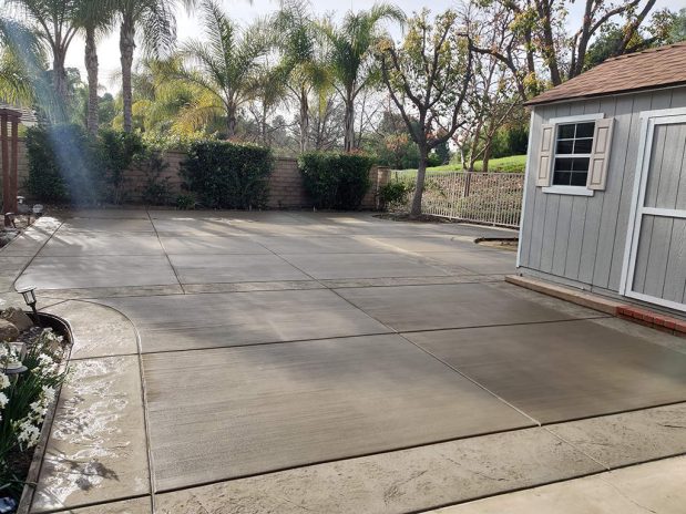 A concrete patio with a shed in the background.