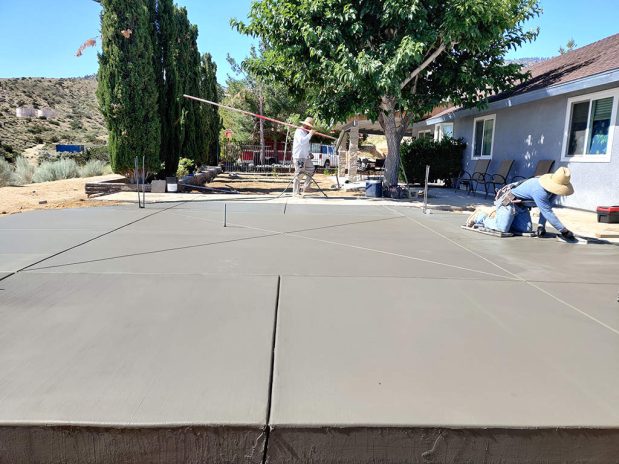 Concrete patio installation, featuring a modern design with sleek lines and a spacious layout.