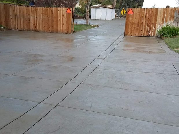A concrete driveway with a backdrop of palm trees and a sunny sky.