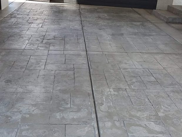 A concrete driveway with a closed garage door in the background.